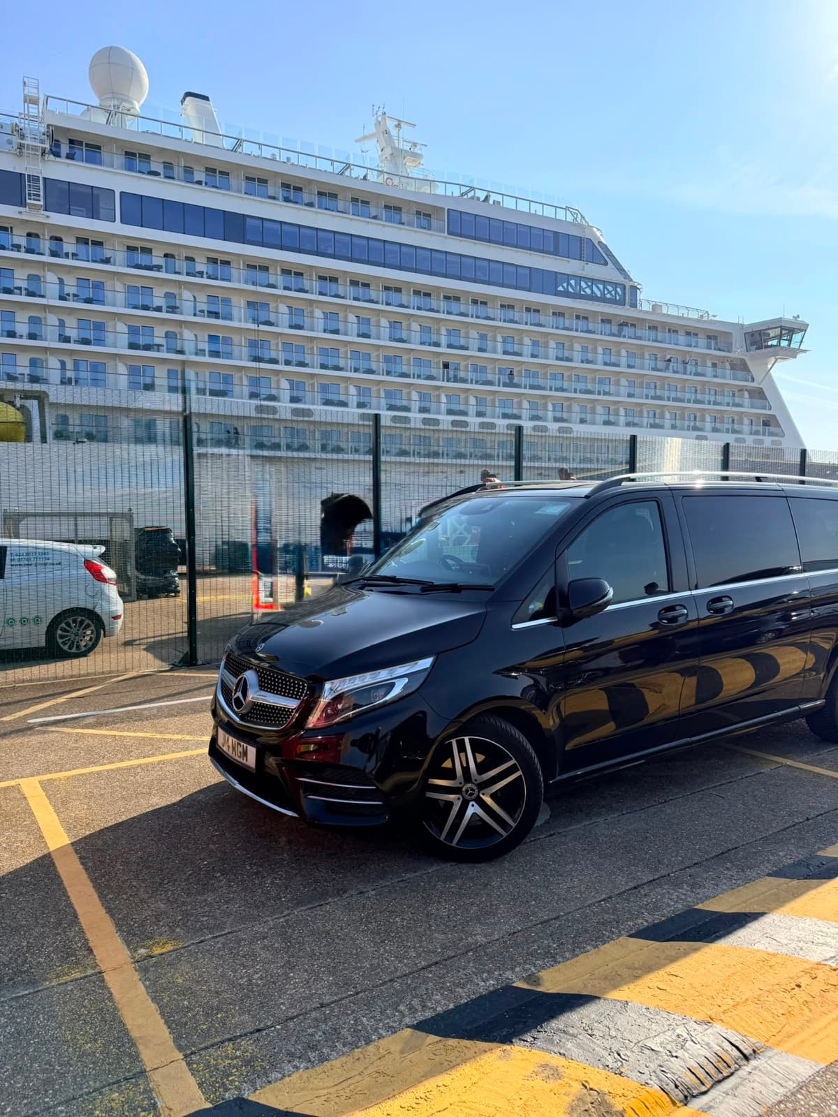 Chauffeur loading luggage into a Mercedes V-Class outside a cruise terminal