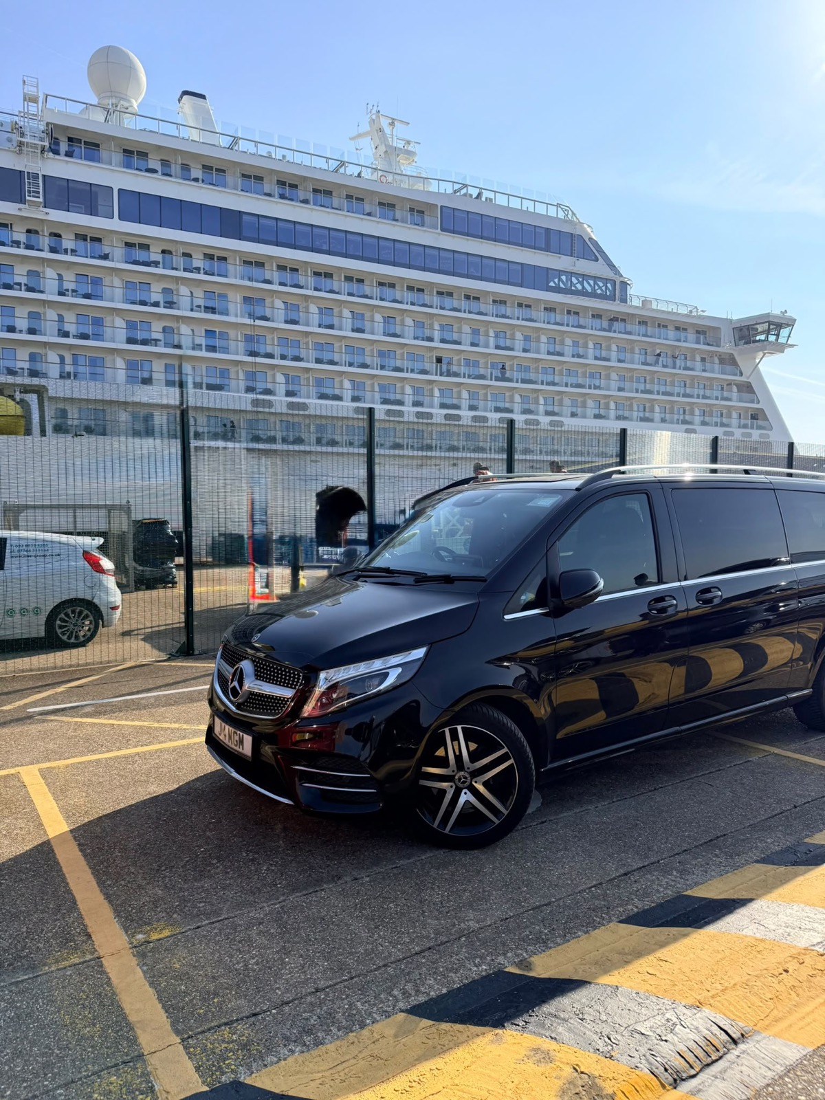 Chauffeur loading luggage into a Mercedes V-Class outside a cruise terminal